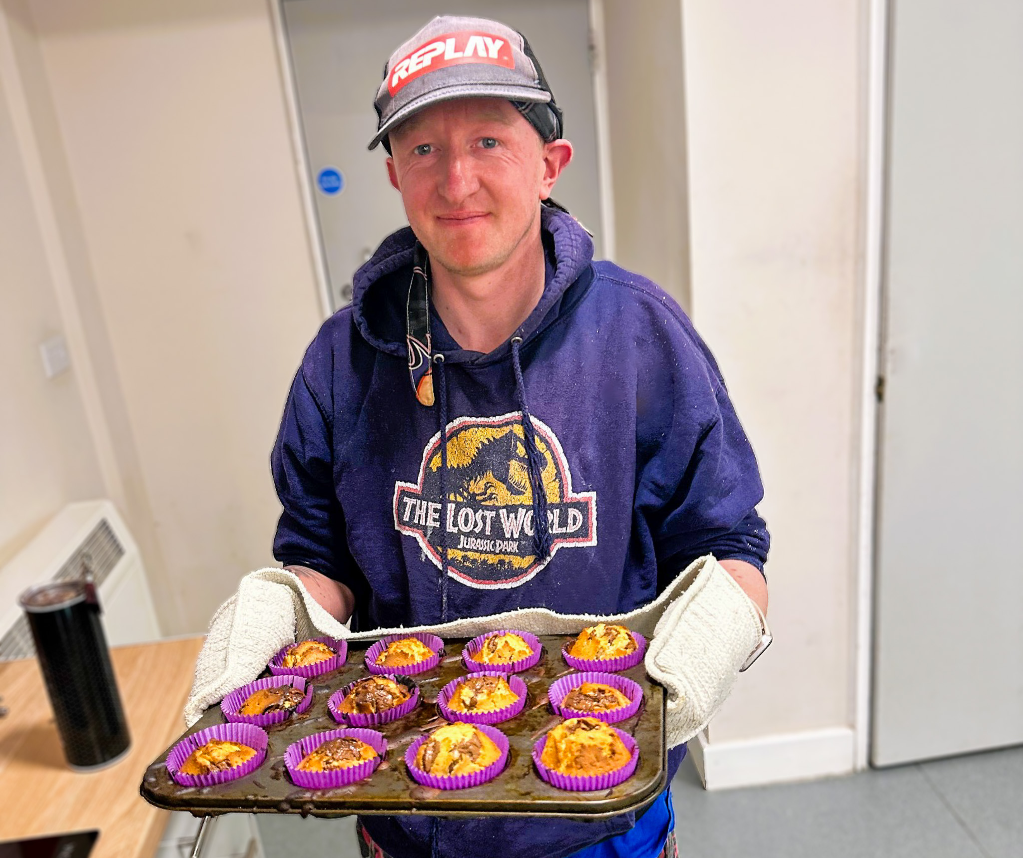 Gentleman carrying baking tray full of cakes