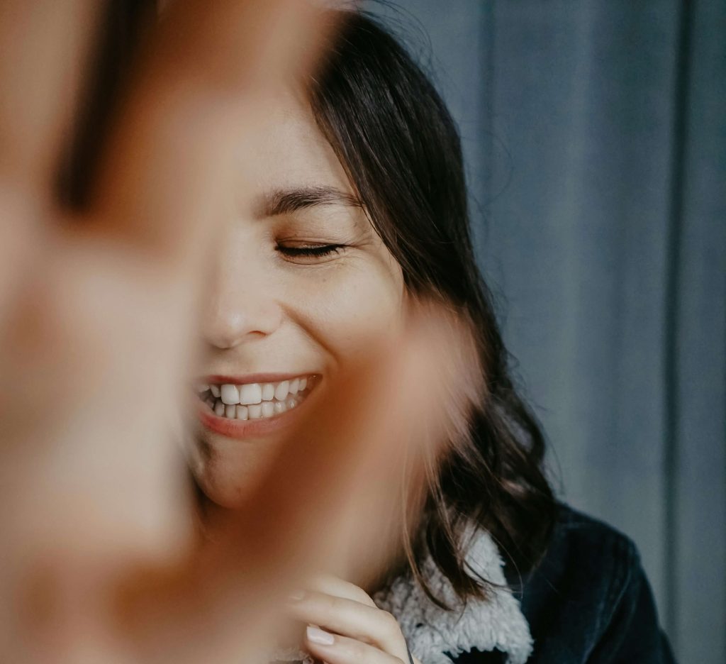 Woman building her self-esteem, laughing and covering the camera with her hand